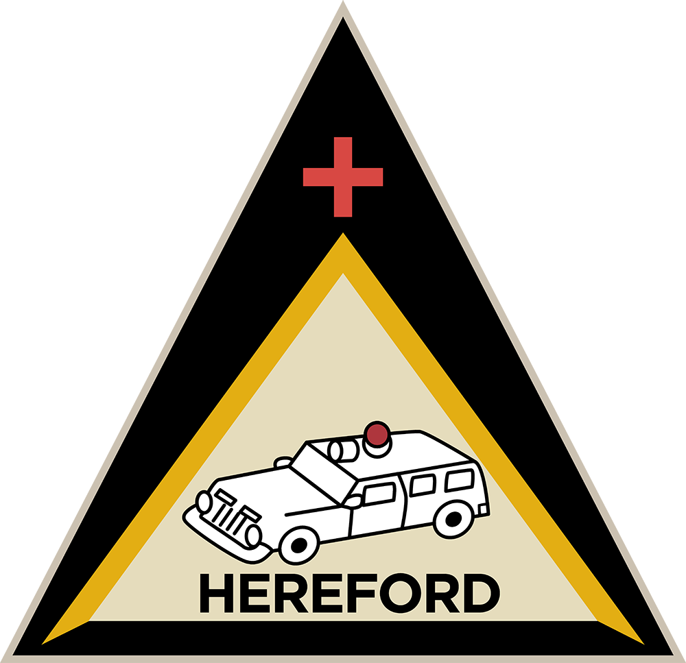 A triangular badge with a red cross at the top, a white armored vehicle with a red light in the center, and the word "HEREFORD" below the vehicle, all on a black and yellow background.
