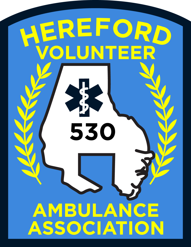 A patch with "Hereford Volunteer Ambulance Association" in yellow text, a white map outline with a medical symbol and the number 530, flanked by yellow laurel branches on a blue background.